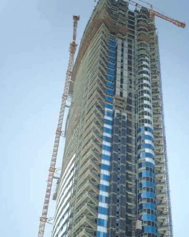 High-rise tower under construction with cranes and façade works